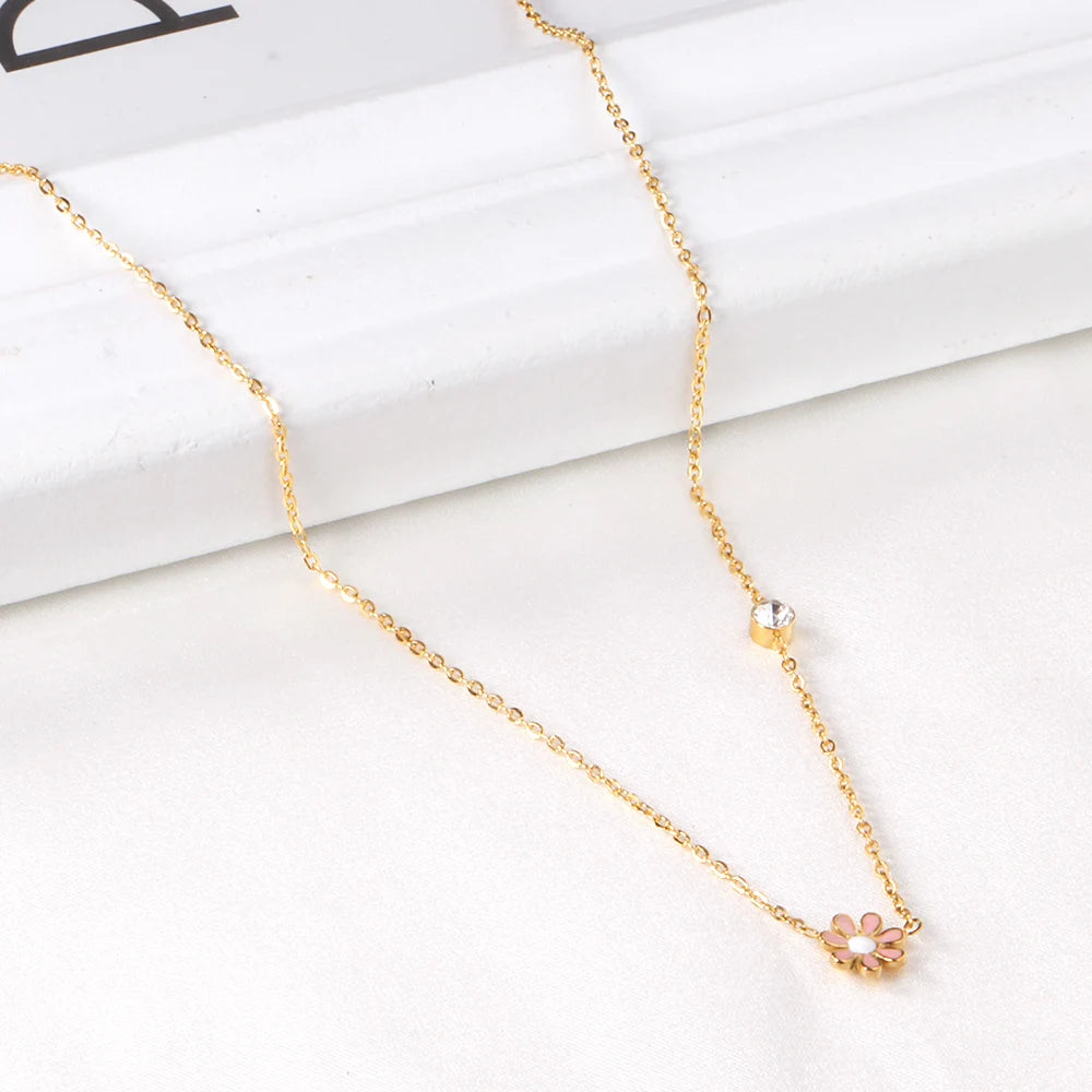 Daisy necklace featuring a pink enamel daisy pendant and clear CZ accent on a gold-plated chain.