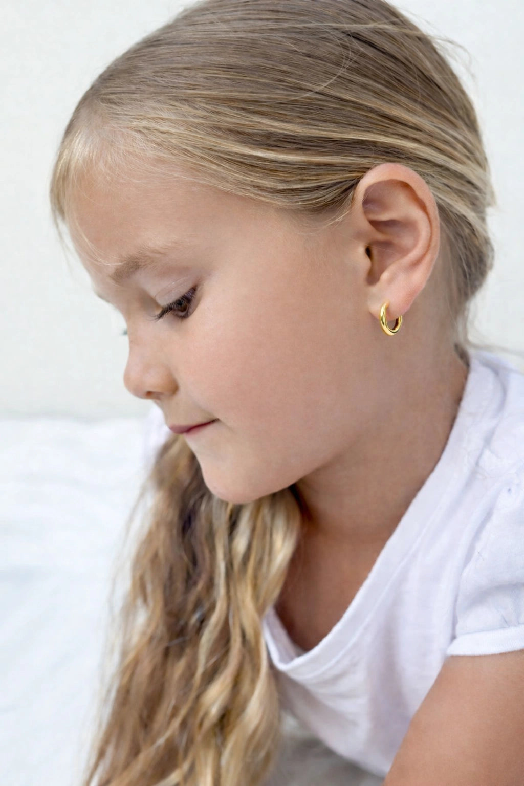 Young girl wearing children's earrings 18k gold plated surgical steel hoop earrings in 10mm size.