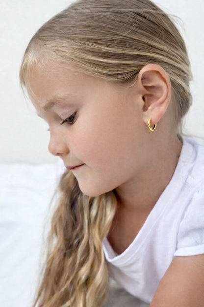 Young girl wearing children's earrings 18k gold plated surgical steel hoop earrings in 10mm size.
