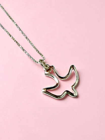 Silver necklace with a cat-shaped pendant on a pink background