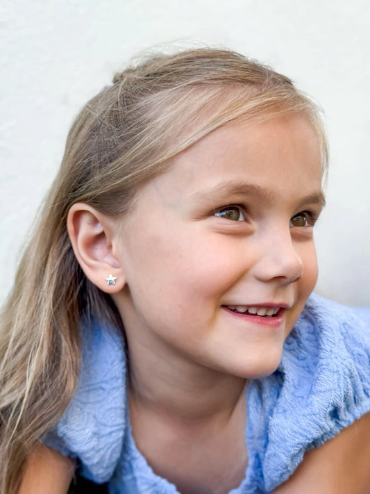 Young girl with blonde hair wearing a blue towel around her neck against a white background