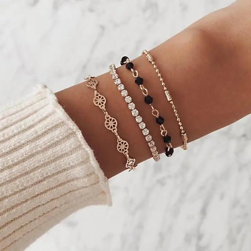Layered bracelet set featuring three bracelets with black crystal accents worn on a wrist against a white background.