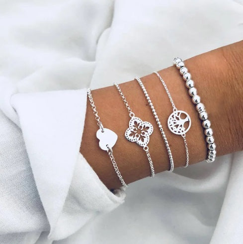 Layered bracelet set featuring three silver bracelets with heart and tree of life designs, perfect for chic styling.
