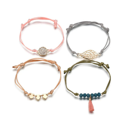 Layered bracelet set featuring four bohemian cord bracelets in pink, gray, orange, and green for a chic layered look.