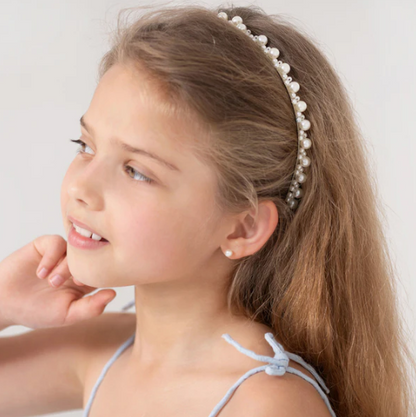 Girl wearing pearl earrings and a pearl headband, showcasing elegant style and charm.