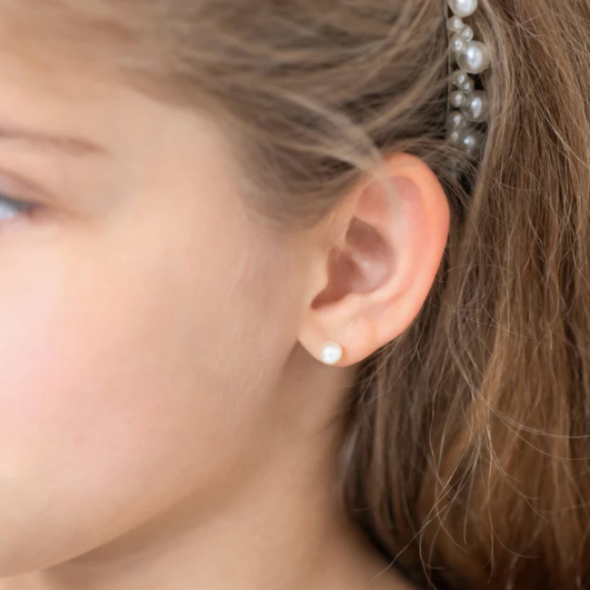 Close-up of girl wearing pearl earrings, showcasing 14k yellow gold freshwater cultured pearl screw backs.