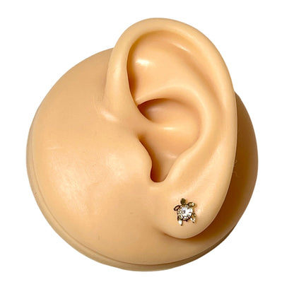 Turtle earrings featuring solid 14k yellow gold filigree design and clear CZ, showcased on ear model.