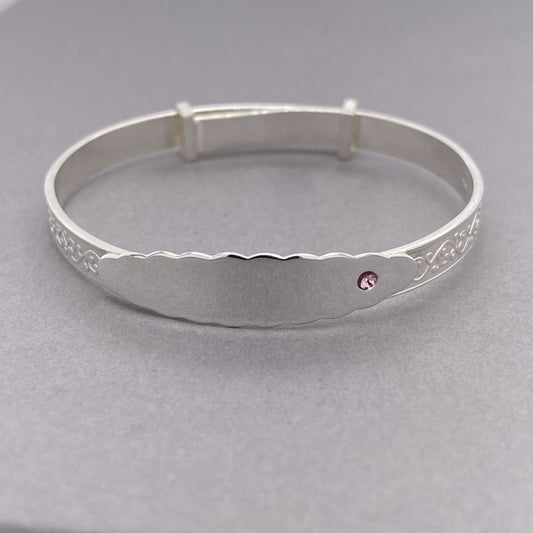 Silver expanding baby bracelet with embossing and name plate featuring a single pink cz stone 