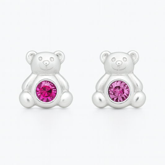 Pair of sterling silver teddy bear stud earrings on a white background, each bear featuring polished rounded ears, arms, and legs, with a vibrant pink crystal set at the centre of its belly.