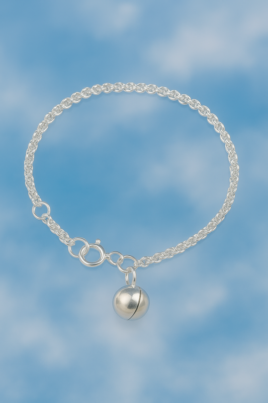 Sterling silver children’s bracelet with musical bell charm – flat lay view - on blue sky background