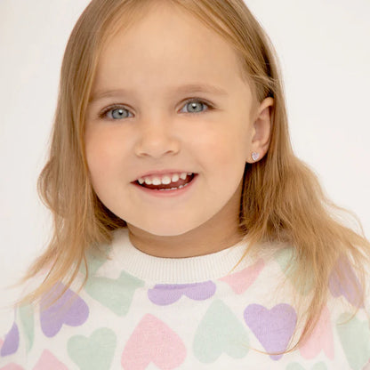 Young girl wearing a pastel heart-patterned sweater on a white background