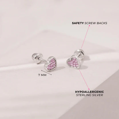 Heart-shaped earrings with pink stones on a light gray background, featuring safety screw backs and hypoallergenic sterling silver details.