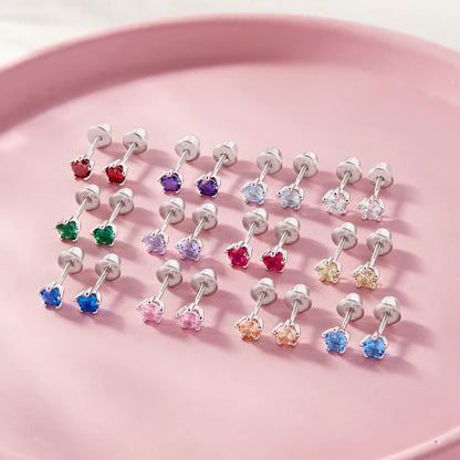 Sterling silver birthstone stud earrings for girls with screw backs displayed on a pink plate.