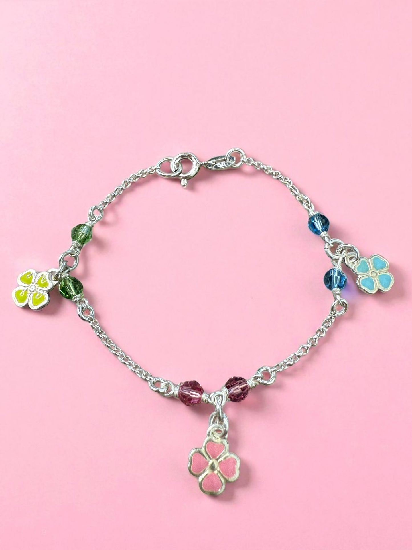 Silver bracelet with colorful flower charms on a pink background
