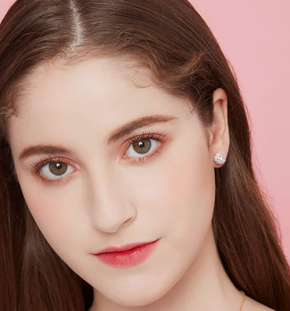 A young teen aged girl with brown hair wearing sparkling disco ball earrings in her ears with a pink background