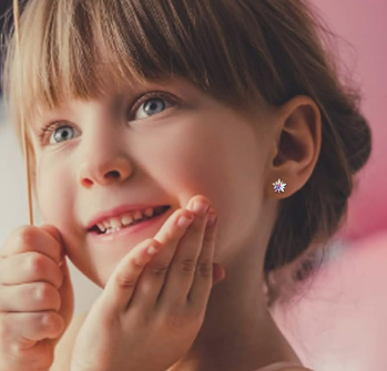 a little girl with star studs in her ears against a blurred pink background