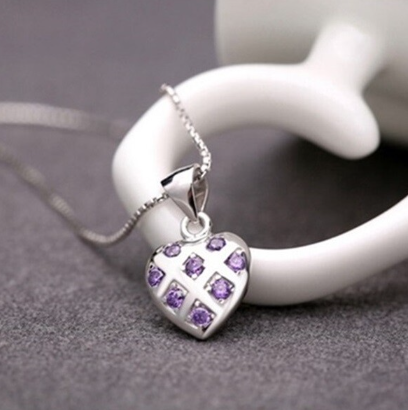 A sterling silver and purple cz heart shaped pendant on a silver chain with a light grey background