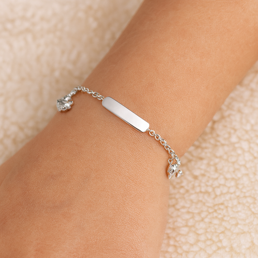 Silver bracelet with a bar charm on a wrist against a beige background