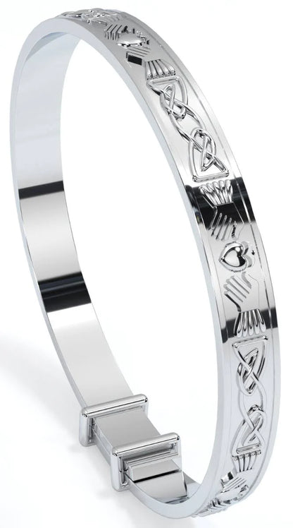Sterling silver expandable baby bangle engraved all around with Claddagh heart, hands, and crown motifs in a continuous Celtic knot pattern, shown on a white background standing on its side