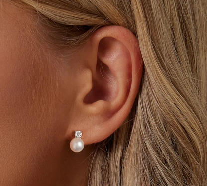Close-up of child wearing pearl stud earrings with sparkling Moissanite top – elegant gift look