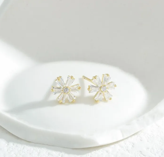 Gold snowflake earrings on a white surface