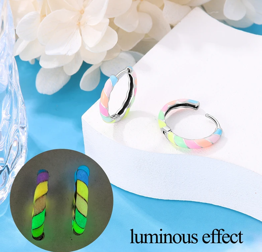 Colorful hoop earrings with a glowing effect on a blue surface with flowers.