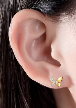 Model wearing small gold butterfly stud earring with sparkling detail, positioned on earlobe