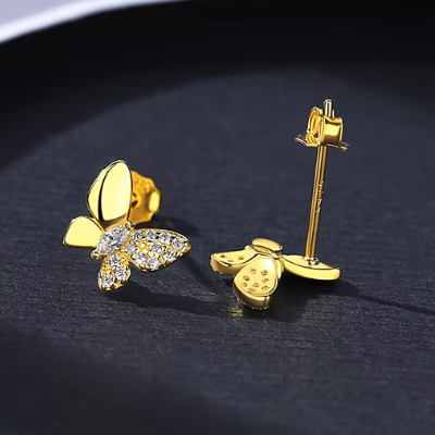 Gold butterfly-shaped earrings on a dark background with one earring face down to reveal the post and butterfly shaped push back