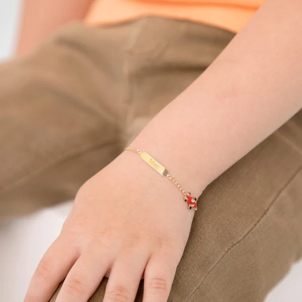 Identity bracelet in 14k yellow gold with red enamel racing car charm on child's wrist.
