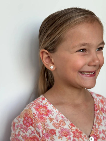 Smiling child wearing 925 sterling silver rainbow CZ paw print studs, showcasing fashionable children's earrings.