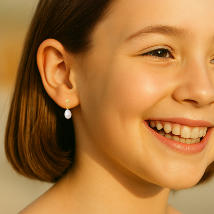 Close-up portrait of a smiling young girl with a chestnut-brown bob, warm golden sunlight illuminating her smooth skin and bright brown eye, her bare ear visible against a softly blurred natural background