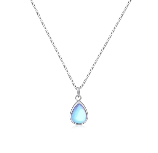 Teardrop-shaped moonstone pendant on a silver chain, displayed on a soft, neutral lifestyle background.