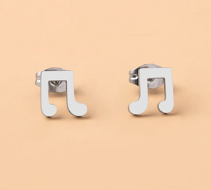 Pair of stainless steel musical note stud earrings displayed on a soft, light lifestyle background