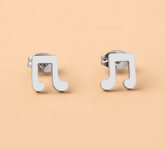 Pair of stainless steel musical note stud earrings displayed on a soft, light lifestyle background