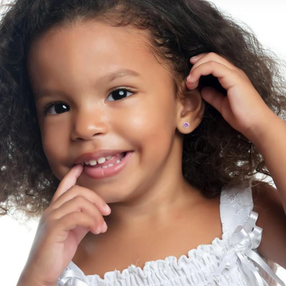 Young girl with curly hair wearing a white top against a neutral background