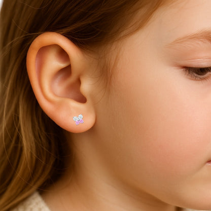 Close-up of a child's ear wearing a small earring shaped like a butterfly with pink and clear cubic zirconia wings