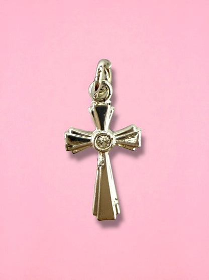Gold cross pendant with a diamond on a pink background