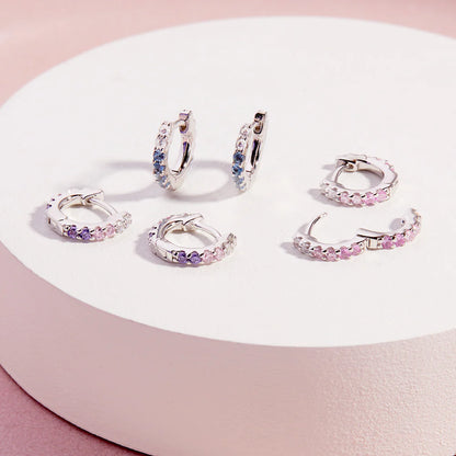 Children's earrings: Sterling silver huggie hoops with blue and pink cubic zirconia gemstones.