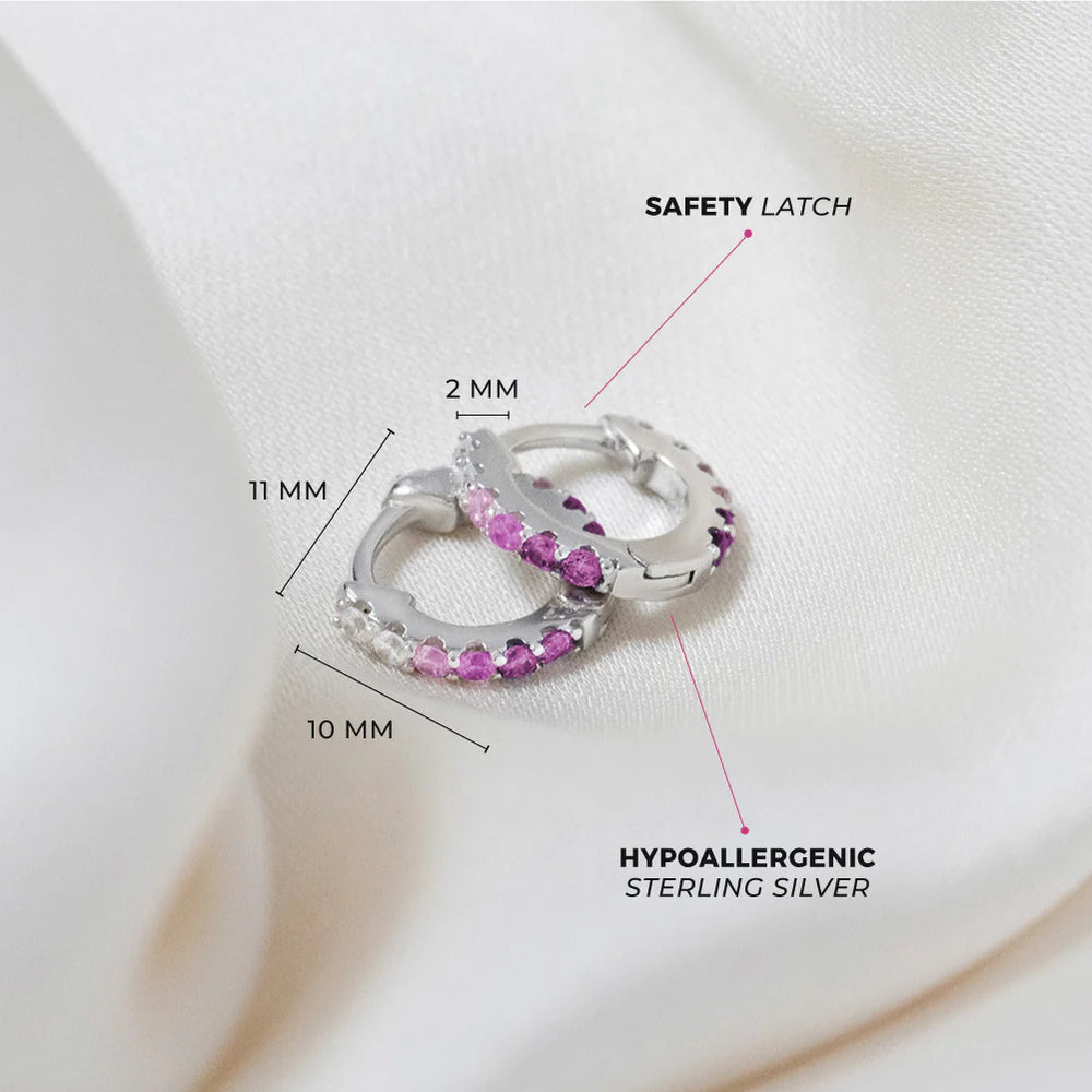 Children's earrings in sterling silver with pink and purple cubic zirconia, featuring a secure huggie hoop design.