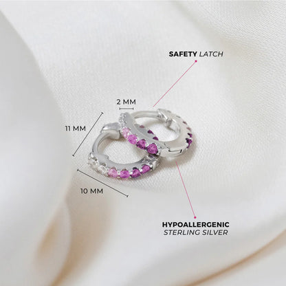 Children's earrings in sterling silver with pink and purple cubic zirconia, featuring a secure huggie hoop design.