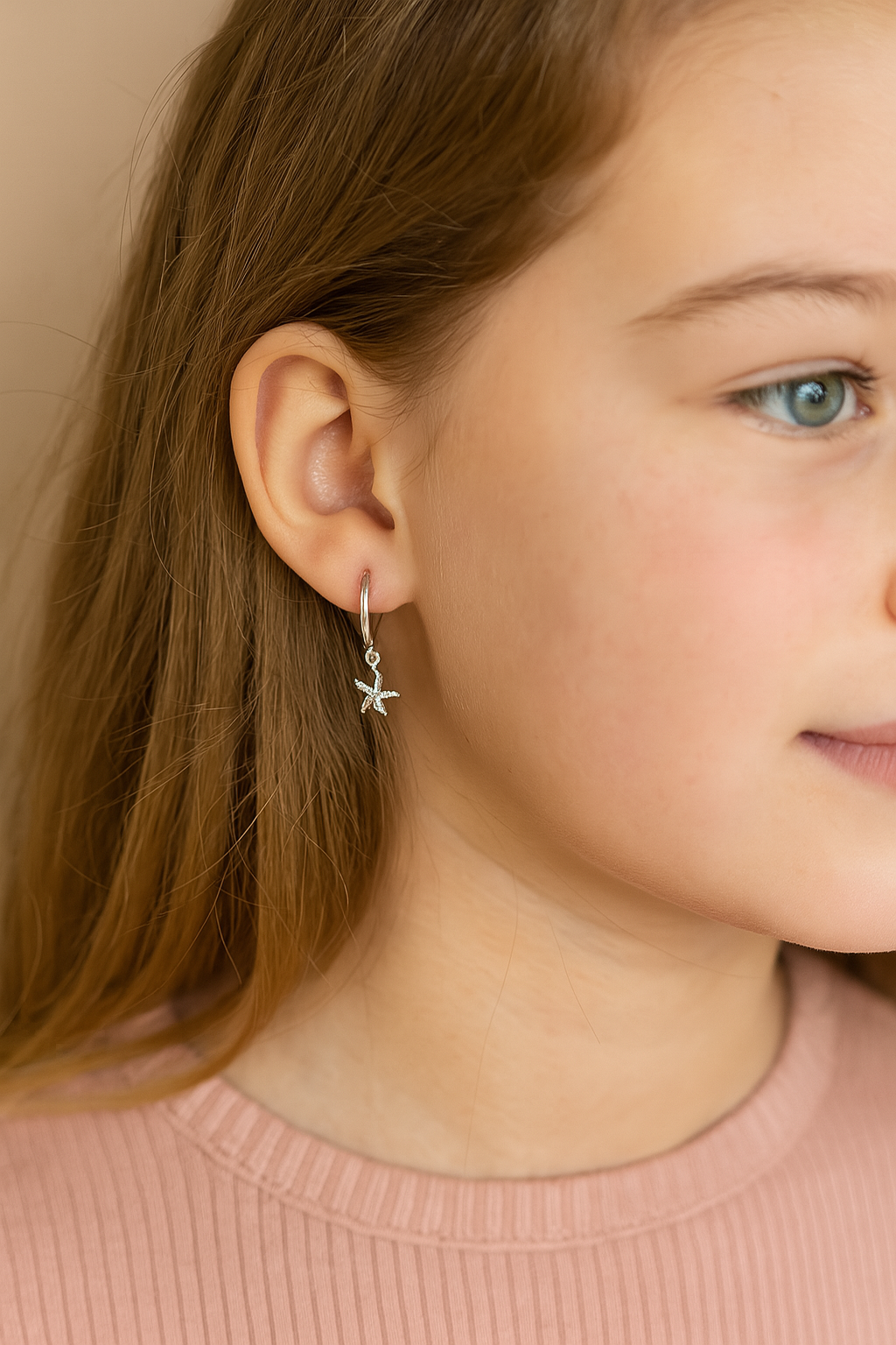 Close-up of a person wearing a starfish earring with a neutral background