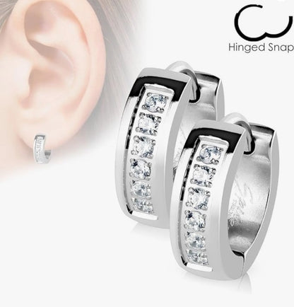 Composite image showing a close‑up of a child’s ear wearing a small sterling‑silver hinged snap hoop earring set with five clear crystals, alongside a larger product shot of two matching hoop earrings encrusted with cubic zirconia, all on a white background