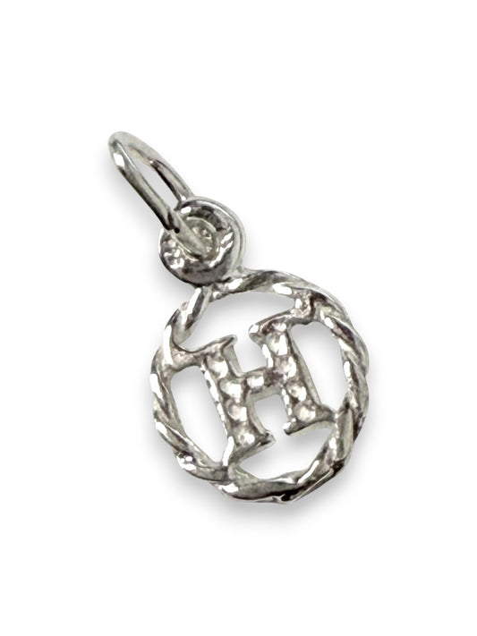 Silver pendant with a circular design and letter 'H' on a white background