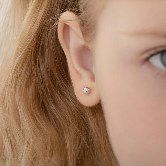 Close-up of child's ear featuring 14k white gold ball stud earrings, perfect children's earrings for everyday wear.