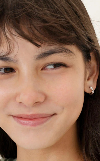 a young girl with brown hair wearing sterling silver hoop earrings with white cz stones