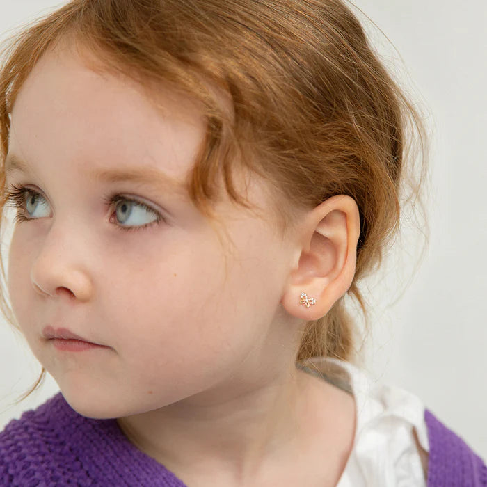 Close up of a little girl with red hair in a purple knitted jumper looking to the left to show off the butterly earring in her ear