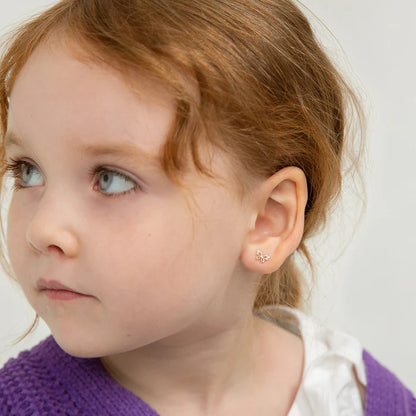 Close up of a little girl with red hair in a purple knitted jumper looking to the left to show off the butterly earring in her ear