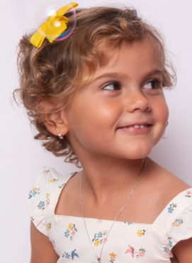 A young girl with curly blonde hair in a summer dress with sterling silver hoops in her ears