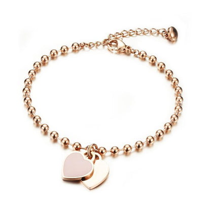 Children's bracelets featuring rose gold IP ball design with pink enamel and engraved heart charms, perfect for kids.