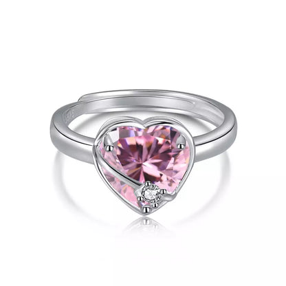 Adjustable sterling silver ring with a pink cubic zirconia heart wrapped in a silver ribbon, with a clear cubic zirconia at the center.